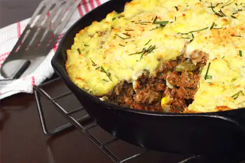 Vegan shepherd's pie with lentils and mashed potatoes in black backing dish. Vegan food concept.